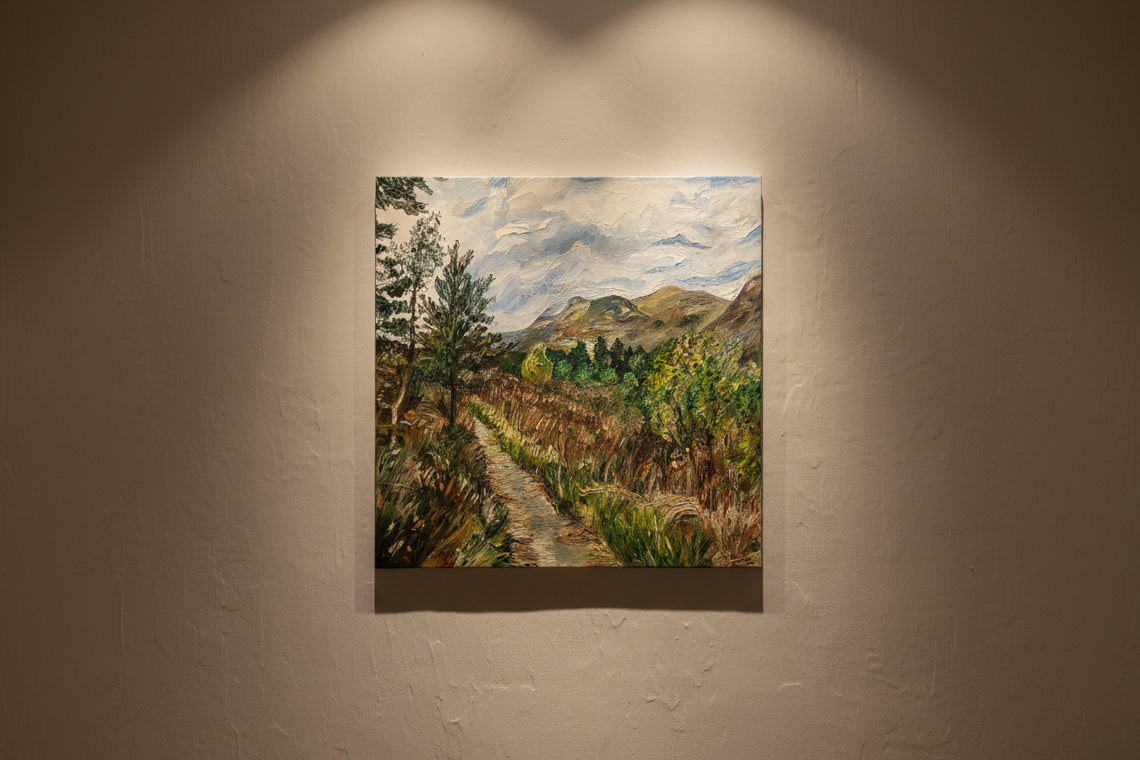Painting of a landscape with trees and mountains on a wall.